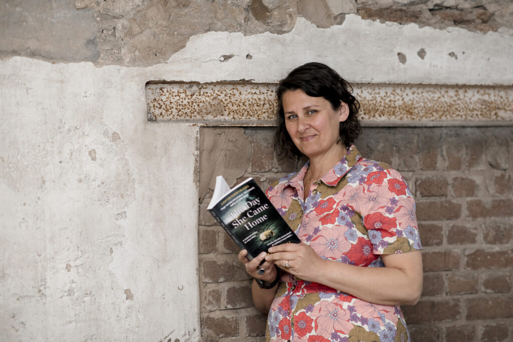 woman leaning against an internal wall and reading a book